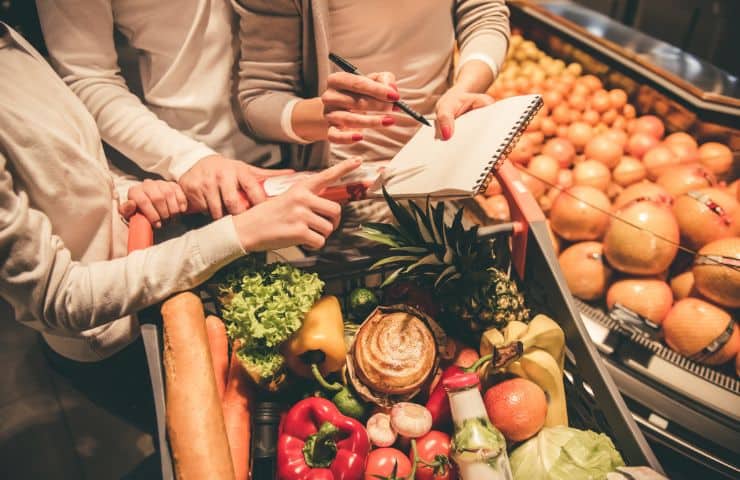 famiglia al supermercato davanti al carrello con lista della spesa